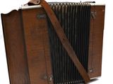 an old wooden accordion with a leather strap on a white background