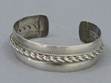 silver cuff bracelet with braid design on a gray background