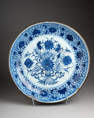 a blue and white plate with flowers on it on a stand