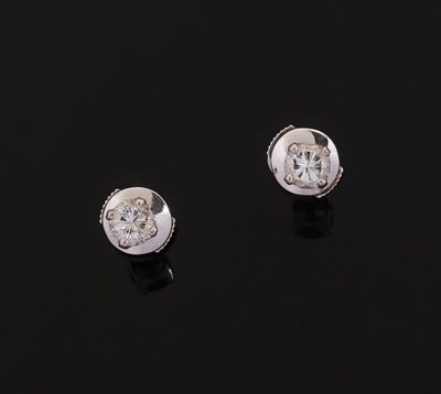 a pair of diamond stud earrings on a black surface