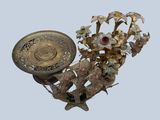 a gold vase with flowers and a plate on it