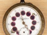 a pocket watch on a wooden table with a clock face