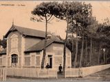 une vieille photo d'un homme debout devant une maison