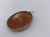 a close up of a silver pendant with a brown stone in it