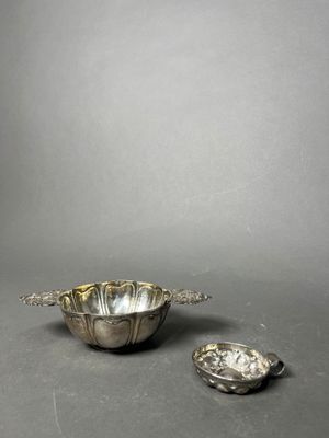 a silver bowl and spoon on a table with a gray background