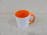 an orange and white coffee mug sitting on top of a table
