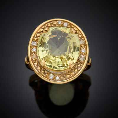 a close up of a yellow sapphire and diamond ring on a black surface