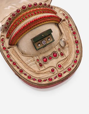 une boîte dorée ornée d'un motif rouge et vert