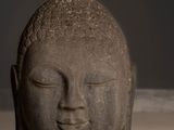a statue of a head and a green apple on the floor