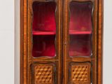 an old wooden cabinet with red glass doors and a wooden shelf