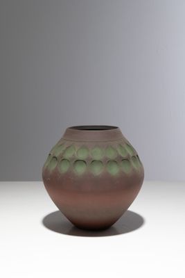 un vase marron et vert posé sur une table blanche