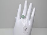 une image représentant une main blanche avec une bague verte au doigt