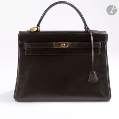 un sac à main en cuir noir avec des finitions dorées sur fond blanc