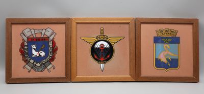 trois photos encadrées représentant différents insignes militaires, accrochées au mur