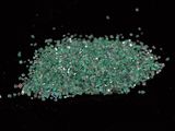 a pile of green crushed glass on a black surface