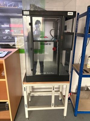 une image représentant un homme debout devant une imprimante 3D