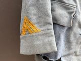 grey jacket with yellow triangle patch on the back of it