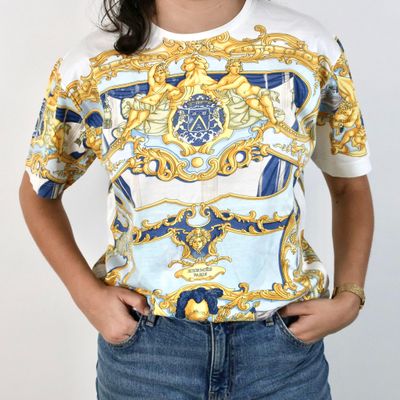 the woman is wearing a white shirt with a blue and gold pattern