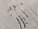 a close up of a grey shirt with silver beads on it