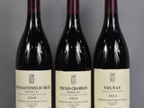 three bottles of red wine are lined up on a table