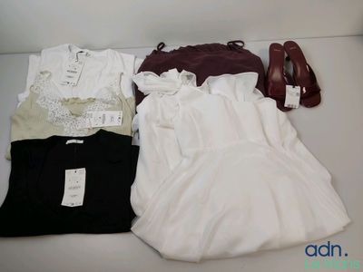 une robe blanche, une chemise noire et une paire de chaussures rouges posées sur une table