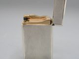 un briquet argenté posé sur une table, devant un fond gris