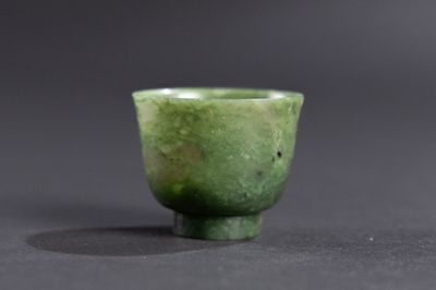 une petite tasse verte posée sur une surface noire