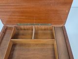 an open wooden box with compartments on a white surface