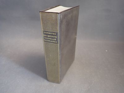 un vieux livre posé sur une table à côté d'un fond gris