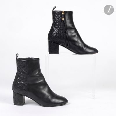 une paire de bottines en cuir noir posées sur un socle en acrylique transparent