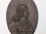 an old bronze medallion of a man with long hair and a beard