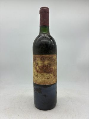 une vieille bouteille de vin posée sur une table blanche