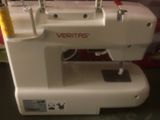 une machine à coudre blanche posée sur une table à côté d'une boîte rouge