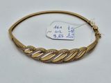 gros plan d'un bracelet en or sur une surface blanche