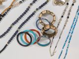 many different types of necklaces and bracelets on the table
