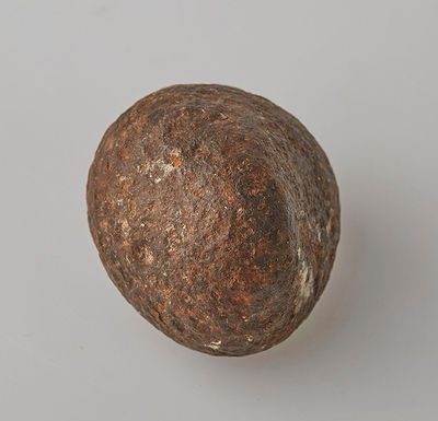 une vieille boule métallique posée sur une surface blanche, avec un fond gris