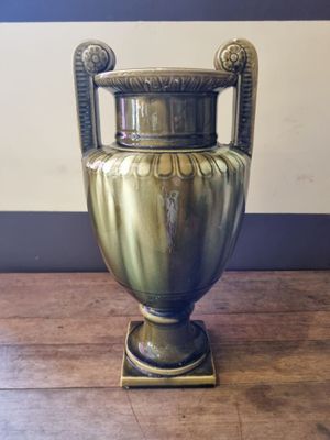 a gold vase on a wooden table with a striped wall in the background