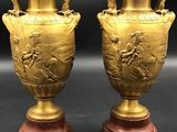 pair of antique bronze vases on wooden bases on a black background