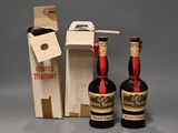 Deux bouteilles d'alcool sont posées à côté d'un carton de vin