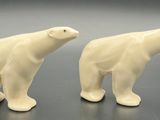 pair of white ceramic polar bear figurines on a black surface