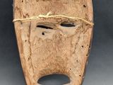 an old wooden mask with a rope wrapped around it ' s face