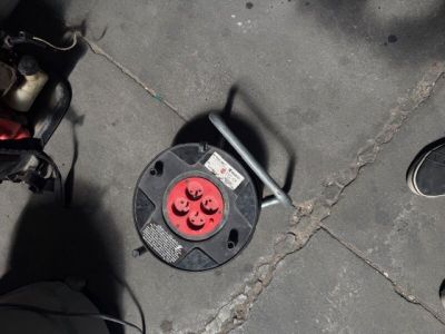 un objet en cordon noir et rouge posé par terre à côté d'une paire de chaussures