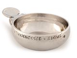 a silver bowl with a spoon in it on a white surface