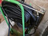 une brouette à laquelle est fixé un tuyau d'arrosage, dans un garage