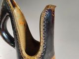 a black and orange vase with a handle on a white surface