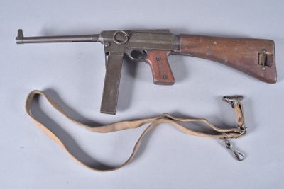 an old machine gun with a sling on a white surface