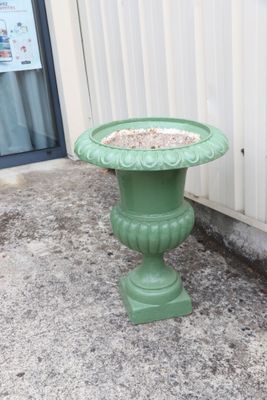 a green birdbath sitting on the sidewalk next to a building