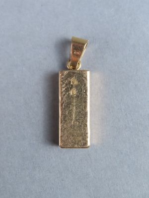 gros plan d'un pendentif en or sur une surface blanche