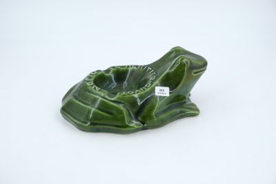 un petit cendrier en forme de grenouille verte posé sur une surface blanche