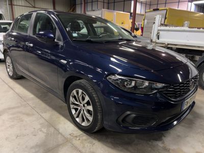 Une voiture bleue est garée dans un entrepôt, à côté d'autres véhicules.